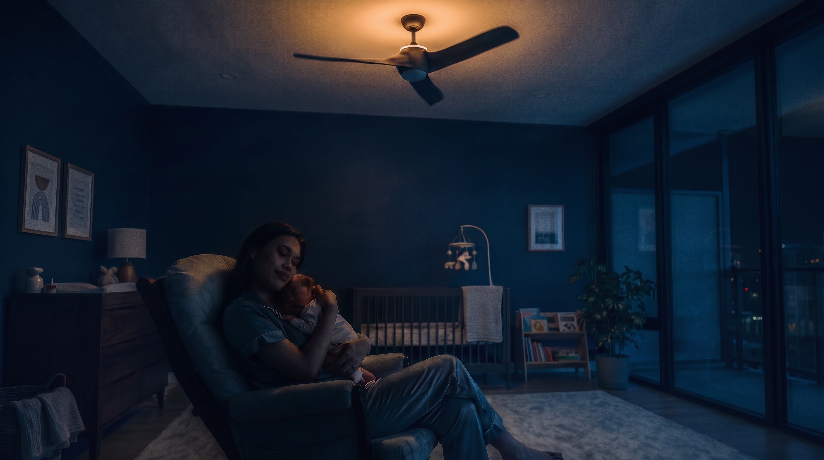 A mother and her baby in a warmly lit nursery beneath a ceiling fan.